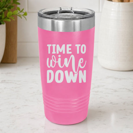 Pink 20 oz tumbler laser engraved with "Time to Wine Down", on a kitchen counter