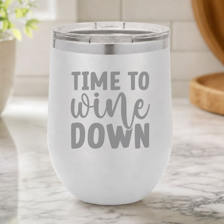 White 12 oz stemless wine tumbler laser engraved with "Time to Wine Down", on a kitchen counter