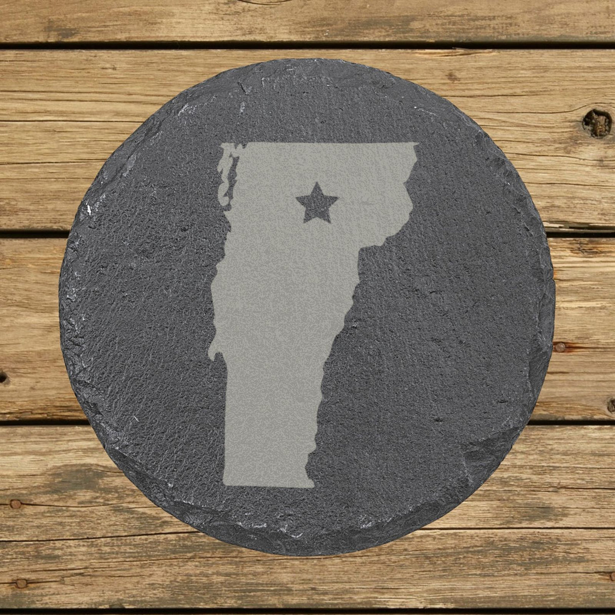 Vermont round slate coaster engraved with the state shape and a star
