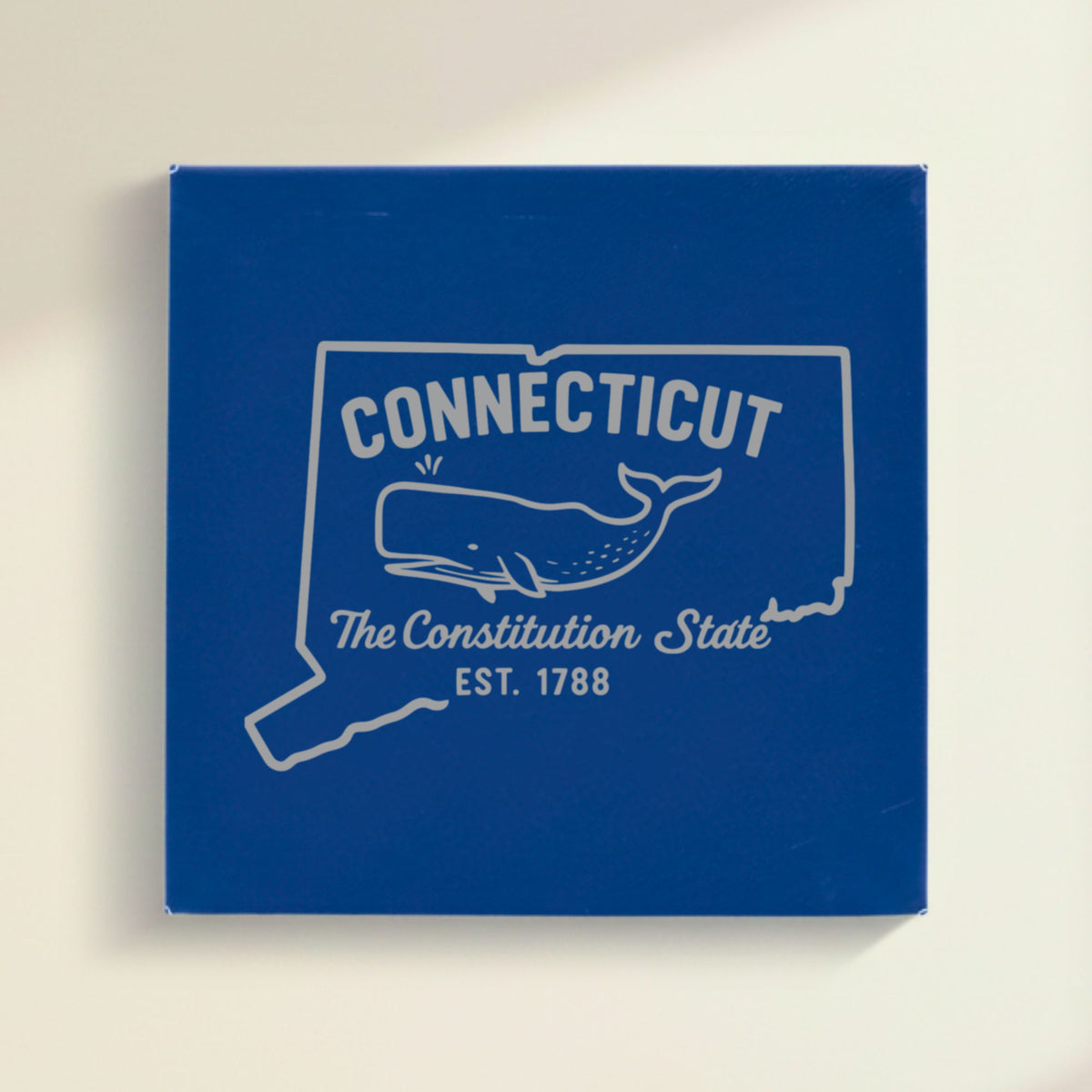 Close up of the Connecticut design engraved on Blue leatherette: a sperm whale, "The Constitution State", EST. 1788
