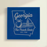 Close up of the Georgia design engraved on Blue leatherette: a peach and the capitol dome, "The Peach State", EST. 1788
