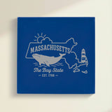 Close up of the Massachusetts design engraved on Blue leatherette: a whale, a lighthouse and the sun over Cape Cod and the islands, "The Bay State", EST. 1788