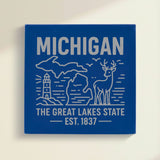 Close up of the Michigan design engraved on Blue leatherette: a lighthouse, a whitetail buck and both peninsulas, "The Great Lakes State", EST. 1837
