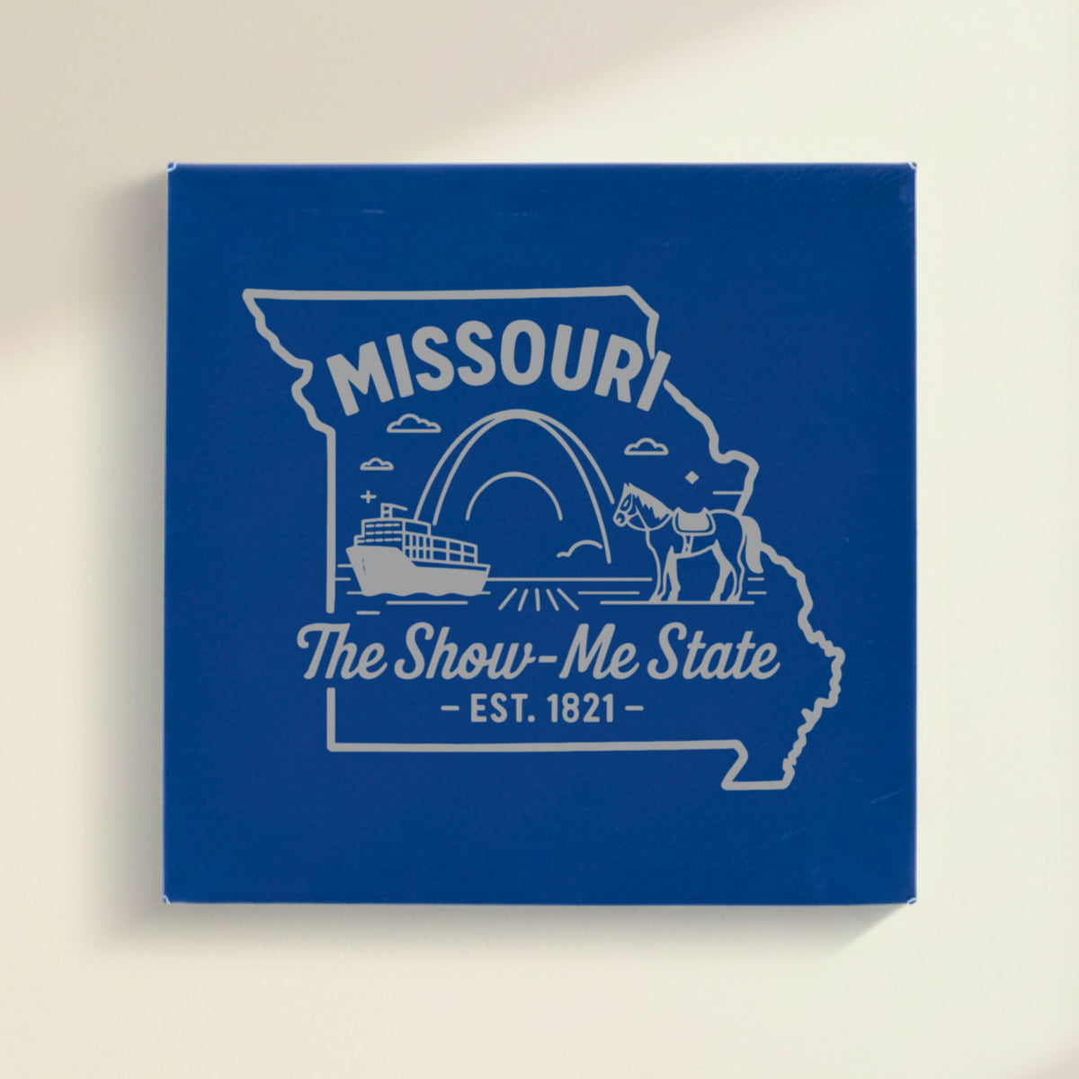 Close up of the Missouri design engraved on Blue leatherette: the Gateway Arch, a riverboat and a mule, "The Show-Me State", EST. 1821