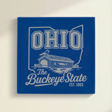 Close up of the Ohio design engraved on Blue leatherette: a covered bridge and a cardinal, "The Buckeye State", EST. 1803