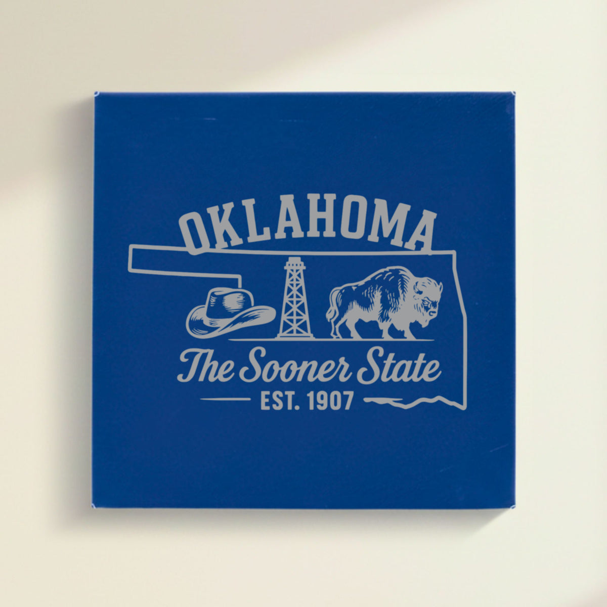 Close up of the Oklahoma design engraved on Blue leatherette: a cowboy hat, an oil derrick and a bison, "The Sooner State", EST. 1907