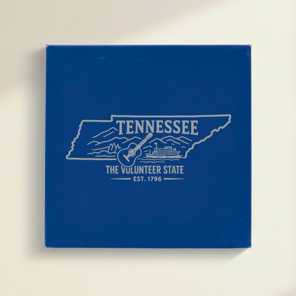 Close up of the Tennessee design engraved on Blue leatherette: a guitar, a riverboat and the Smoky Mountains, "The Volunteer State", EST. 1796