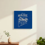 Blue leatherette wall sign engraved with a Maine design of a lobster, pines and a lighthouse, hanging on a wall