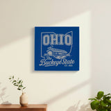 Blue leatherette wall sign engraved with an Ohio design of a covered bridge and a cardinal, hanging on a wall