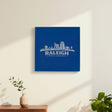 Blue leatherette wall sign engraved with the Raleigh, North Carolina skyline, hanging on a wall
