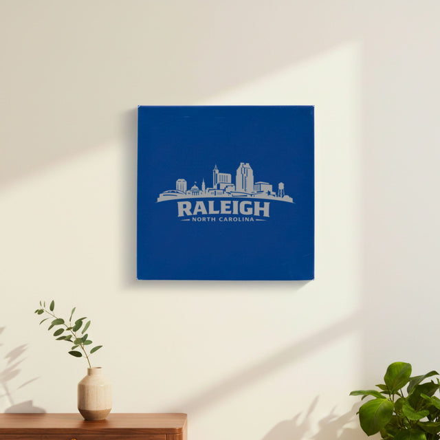 Blue leatherette wall sign engraved with the Raleigh, North Carolina skyline, hanging on a wall