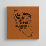 Close up of the California design engraved on Brown leatherette: palm trees, the ocean and a grizzly bear, "The Golden State", EST. 1850