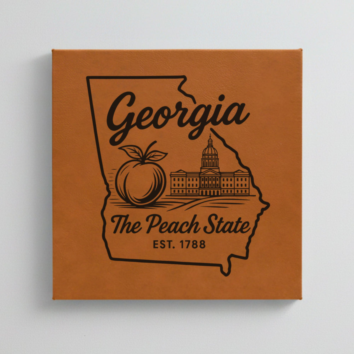 Close up of the Georgia design engraved on Brown leatherette: a peach and the capitol dome, "The Peach State", EST. 1788