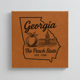 Close up of the Georgia design engraved on Brown leatherette: a peach and the capitol dome, "The Peach State", EST. 1788