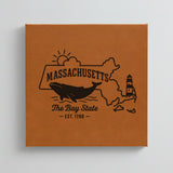 Close up of the Massachusetts design engraved on Brown leatherette: a whale, a lighthouse and the sun over Cape Cod and the islands, "The Bay State", EST. 1788