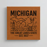 Close up of the Michigan design engraved on Brown leatherette: a lighthouse, a whitetail buck and both peninsulas, "The Great Lakes State", EST. 1837