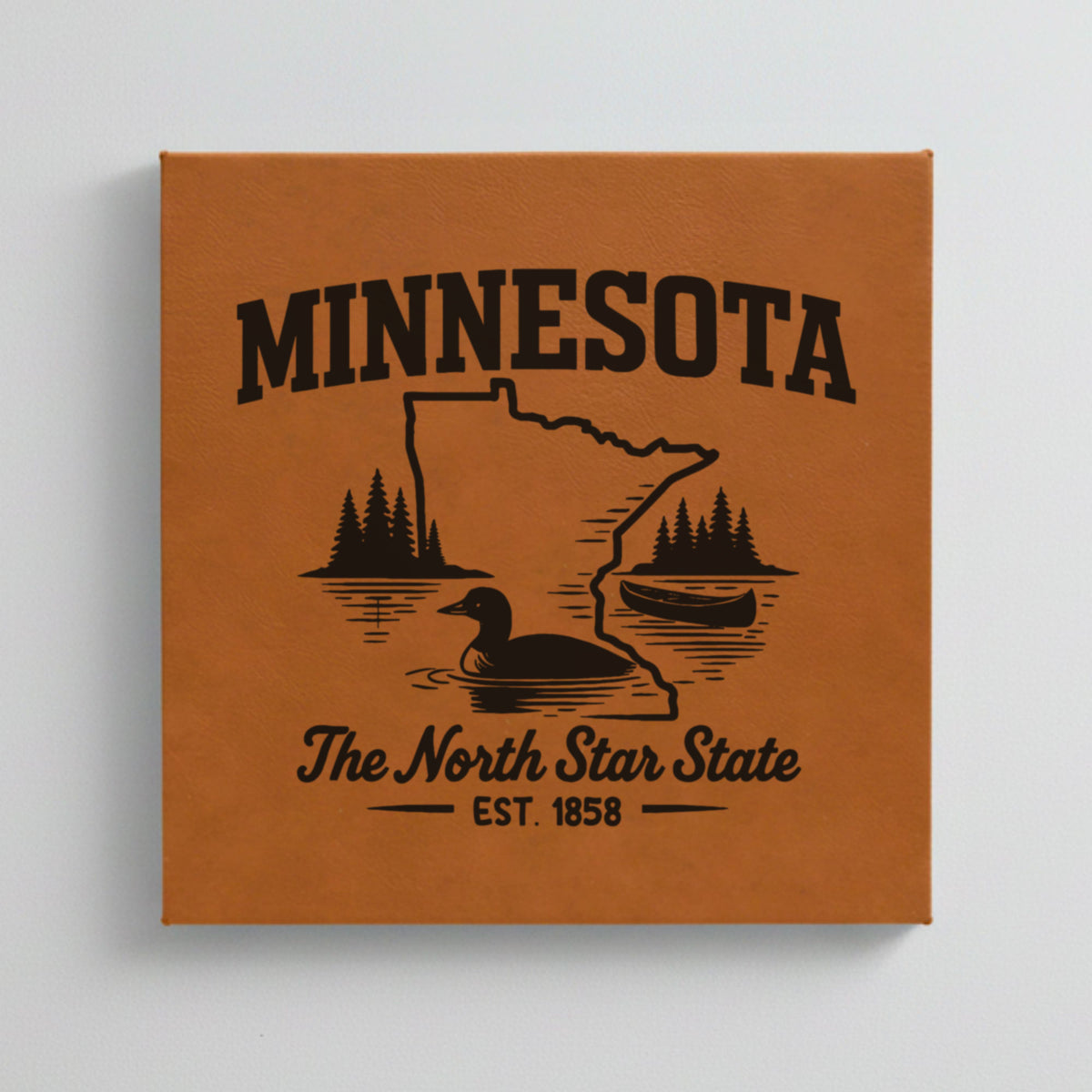 Close up of the Minnesota design engraved on Brown leatherette: a loon, a canoe and lakeside pines, "The North Star State", EST. 1858