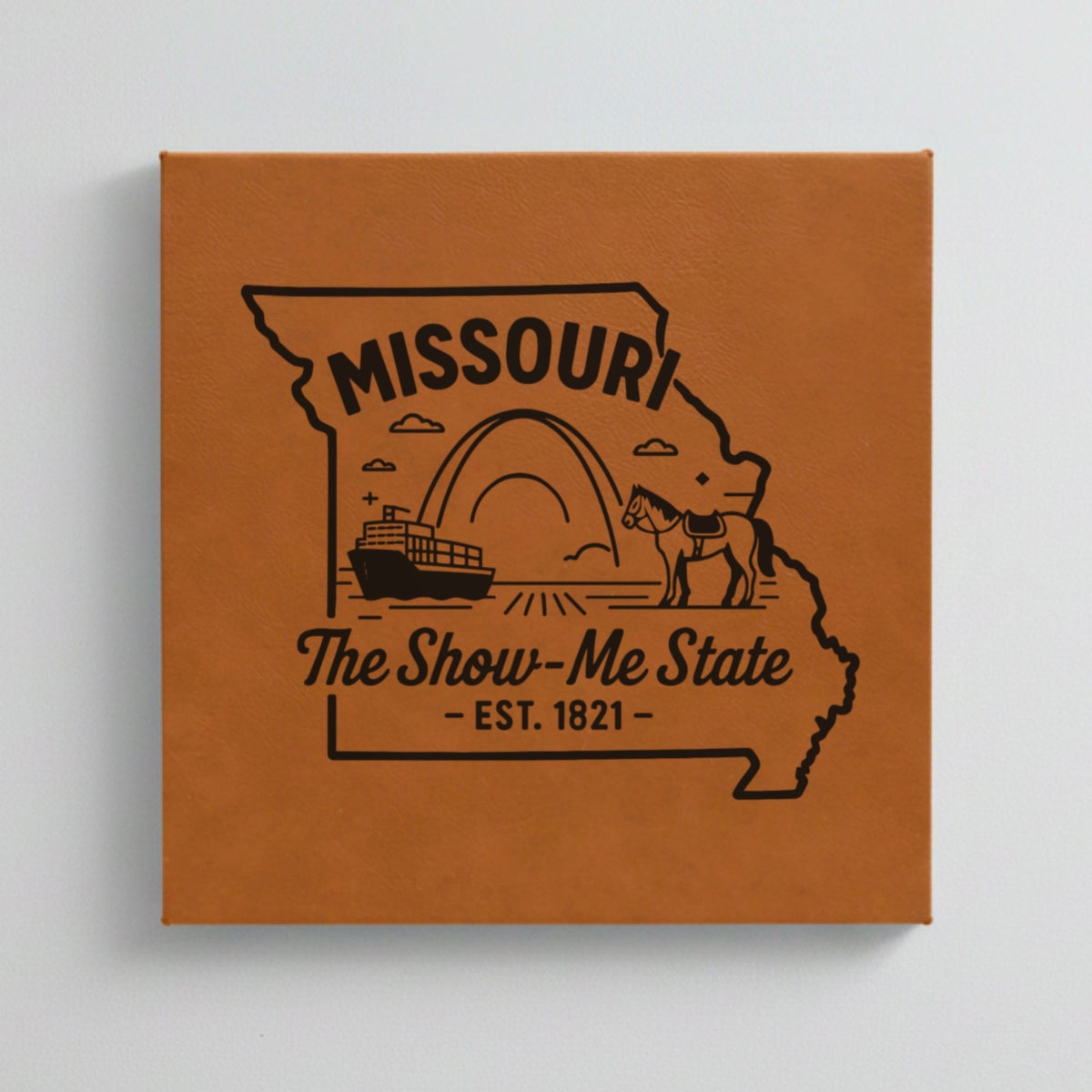Close up of the Missouri design engraved on Brown leatherette: the Gateway Arch, a riverboat and a mule, "The Show-Me State", EST. 1821
