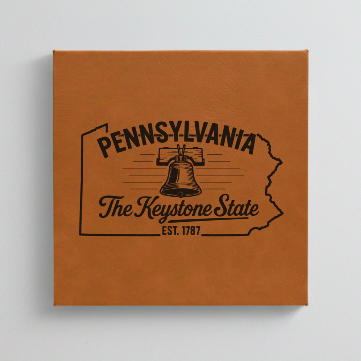 Close up of the Pennsylvania design engraved on Brown leatherette: the Liberty Bell, "The Keystone State", EST. 1787