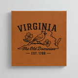 Close up of the Virginia design engraved on Brown leatherette: a cardinal and dogwood blossoms, "The Old Dominion", EST. 1788