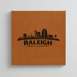 Close up of the Raleigh, North Carolina skyline engraved on Brown leatherette