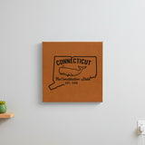 Brown leatherette wall sign engraved with a Connecticut design of a sperm whale, hanging on a wall