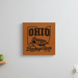 Brown leatherette wall sign engraved with an Ohio design of a covered bridge and a cardinal, hanging on a wall