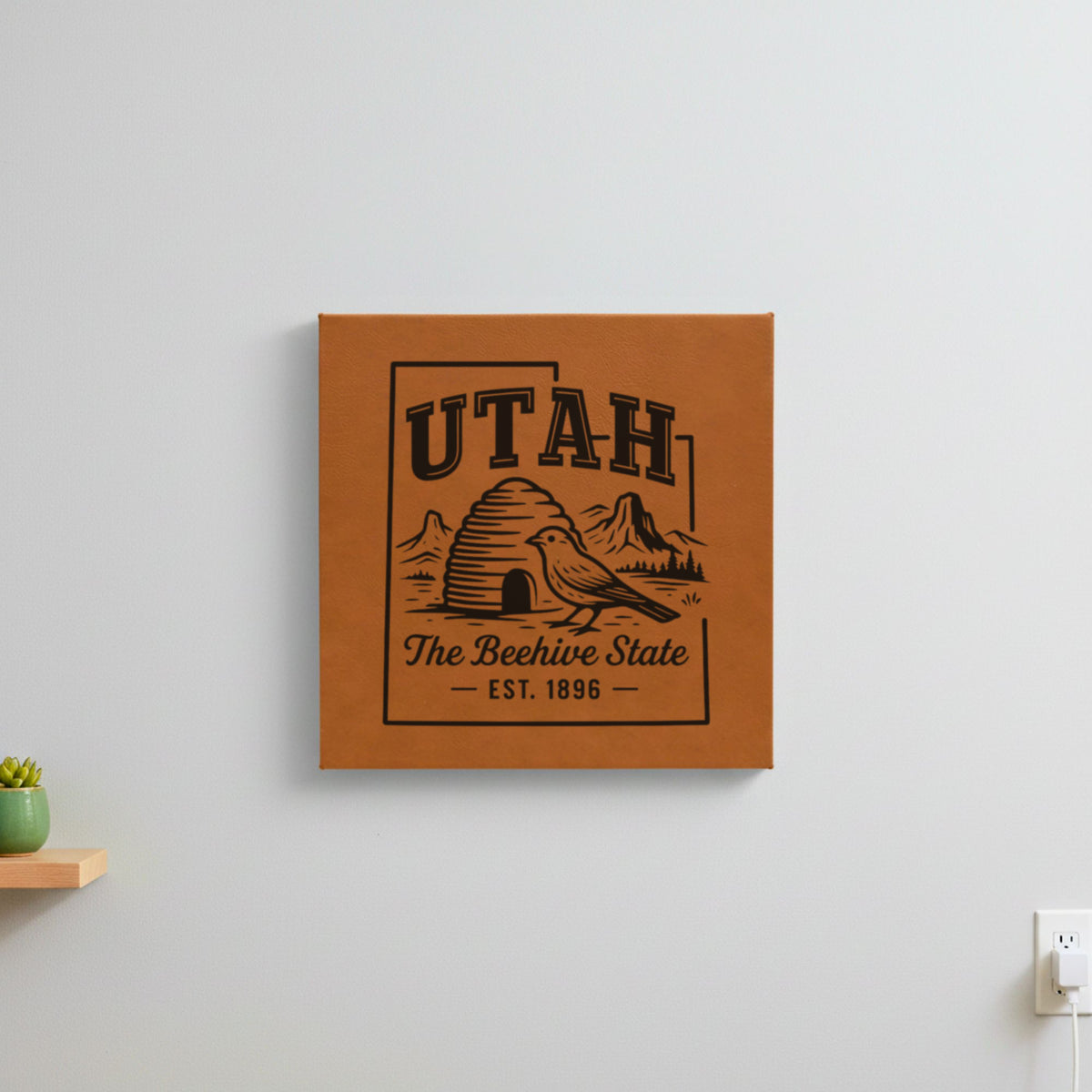 Brown leatherette wall sign engraved with a Utah design of a beehive, a California gull and red rock arches, hanging on a wall
