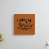 Brown leatherette wall sign engraved with a Virginia design of a cardinal and dogwood blossoms, hanging on a wall