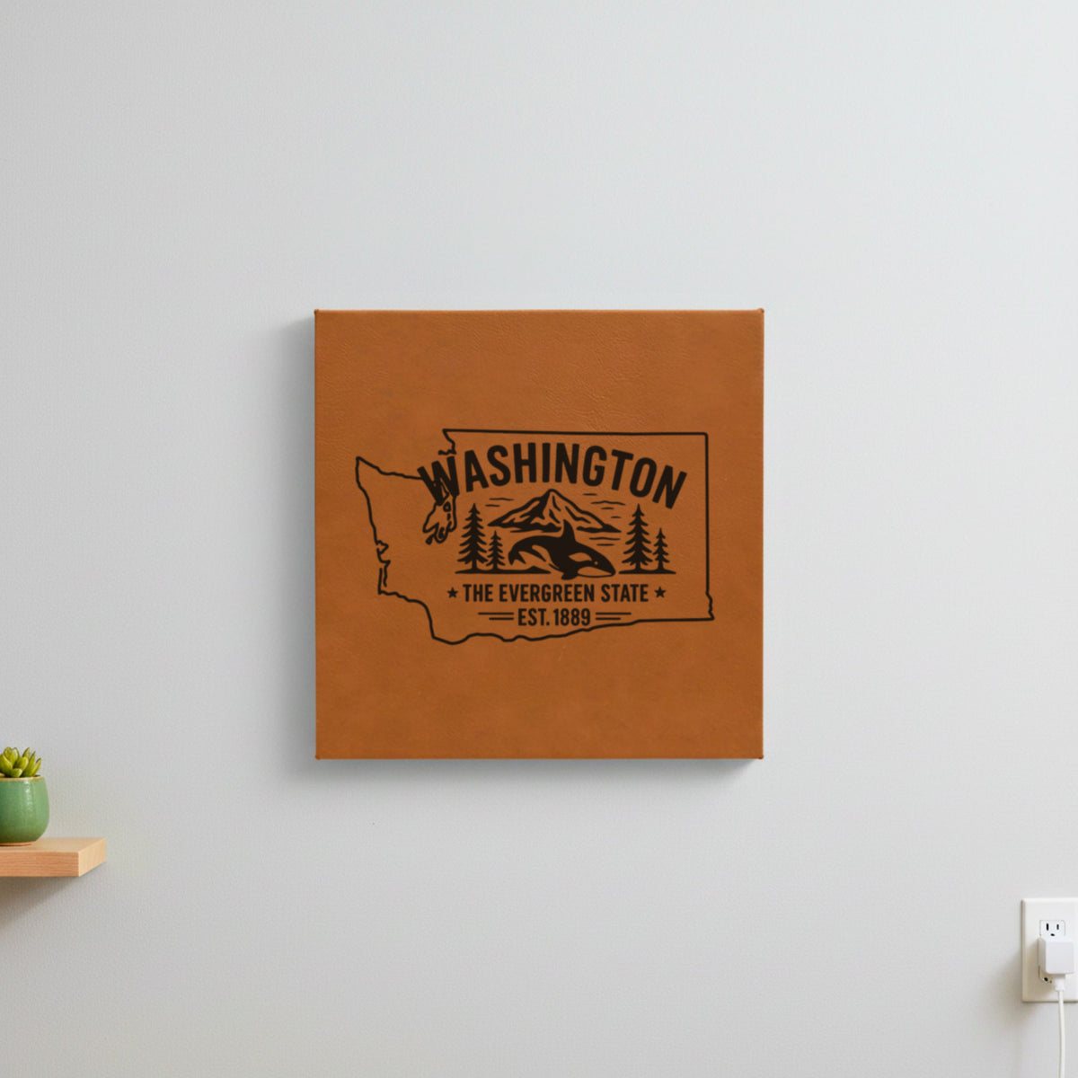 Brown leatherette wall sign engraved with a Washington design of an orca, Mount Rainier and evergreens, hanging on a wall
