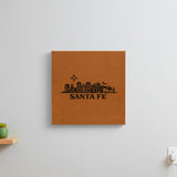 Brown leatherette wall sign engraved with the Santa Fe, New Mexico skyline, hanging on a wall