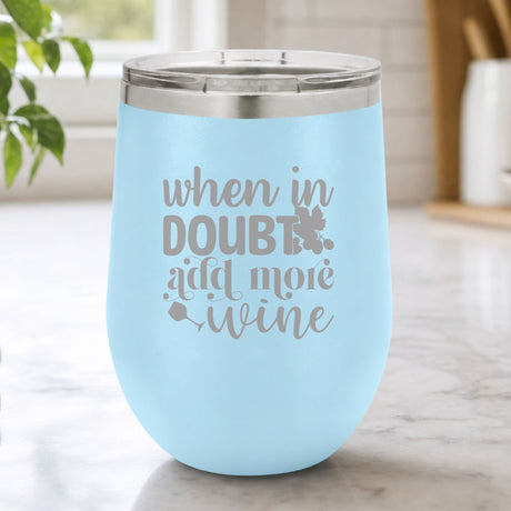 Light Blue 12 oz stemless wine tumbler laser engraved with "When in Doubt, Add More Wine", on a kitchen counter