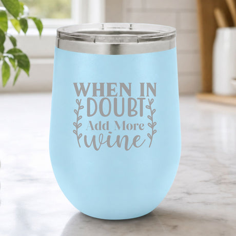 Light Blue 12 oz stemless wine tumbler laser engraved with "When in Doubt, Add More Wine", on a kitchen counter