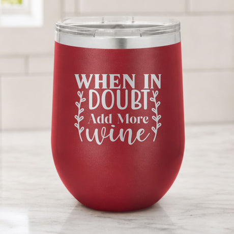 Maroon 12 oz stemless wine tumbler laser engraved with "When in Doubt, Add More Wine", on a kitchen counter
