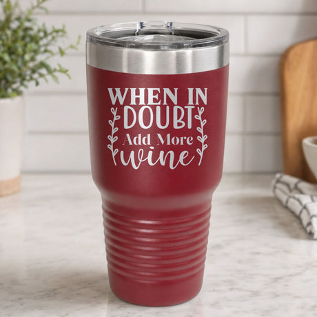 Maroon 30 oz tumbler laser engraved with "When in Doubt, Add More Wine", on a kitchen counter
