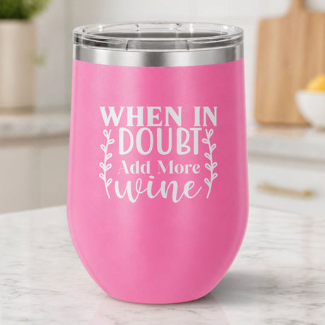 Pink 12 oz stemless wine tumbler laser engraved with "When in Doubt, Add More Wine", on a kitchen counter