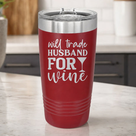 Maroon 20 oz tumbler laser engraved with "Will Trade Husband for Wine", on a kitchen counter