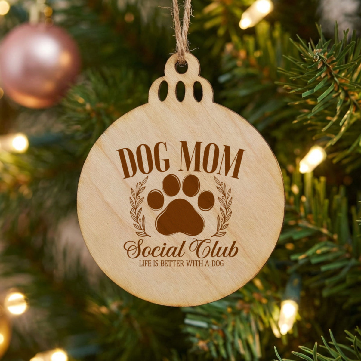 Round natural wood Christmas ornament laser engraved with a Dog Mom Social Club crest design with a paw print and laurel wreath