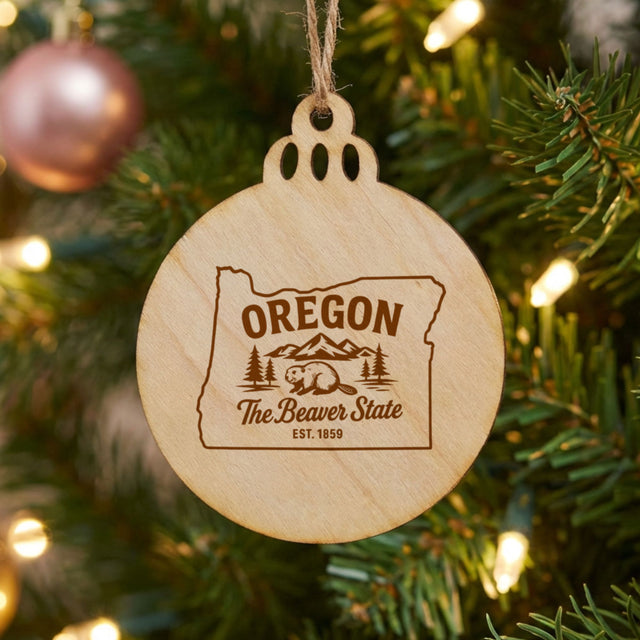 Round wood Christmas ornament laser engraved with an Oregon design of a beaver, mountains and pines