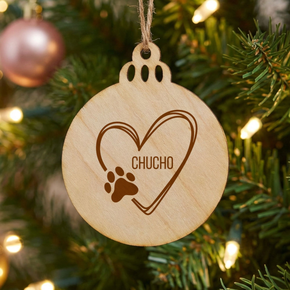 Round natural wood Christmas ornament engraved with the heart and paw print design and a sample pet name