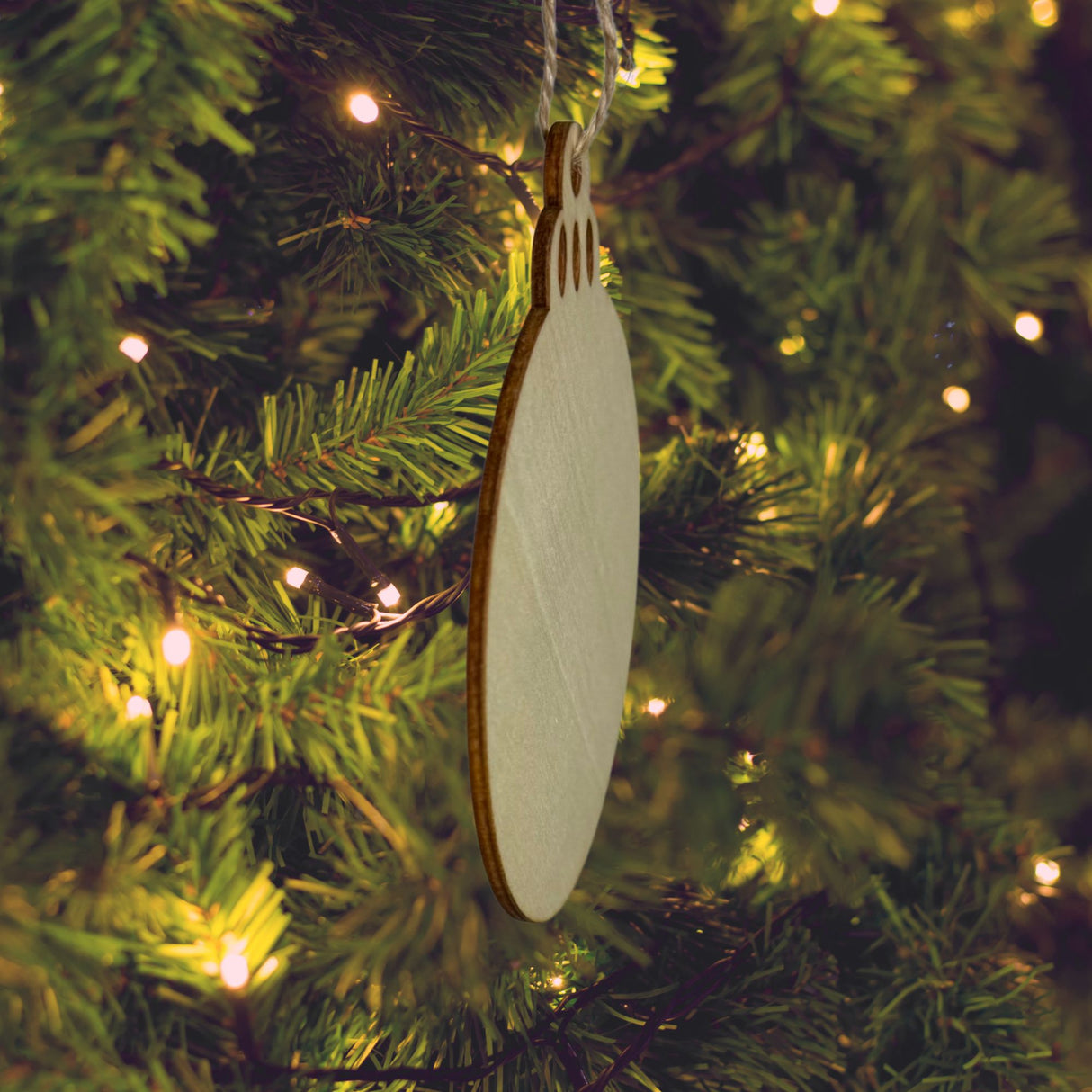 Side view of a round wood Christmas ornament, showing the thickness of the wood