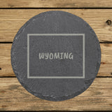 Wyoming round slate coaster engraved with the state outline and WYOMING in hand-drawn brush lettering