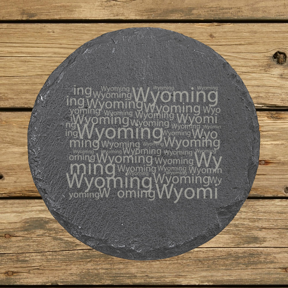 Wyoming round slate coaster engraved with a word cloud of repeating Wyoming text