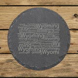 Wyoming round slate coaster engraved with a word cloud of repeating Wyoming text