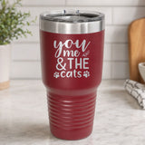 Maroon 30 oz tumbler laser engraved with "You, Me & the Cats", plus paw prints, on a kitchen counter
